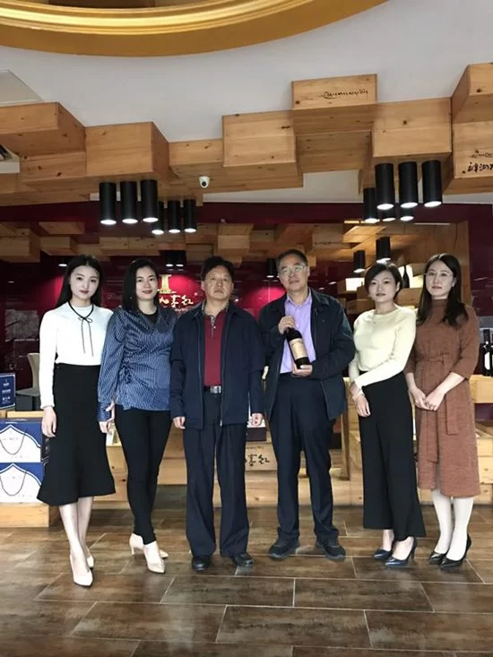 德国前总统武尔夫是如何喝上神沟九寨红的?(图2) 公司员工拿着全球中小企业联盟主席武尔夫签名的“神沟九寨红”合影